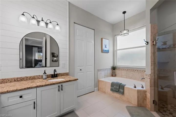 Bathroom with vanity, a closet, a garden tub, a shower stall, and light tile patterned flooring