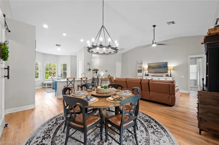 Dining room featuring a chandelier, light wood finished floors, vaulted ceiling, and a ceiling fan