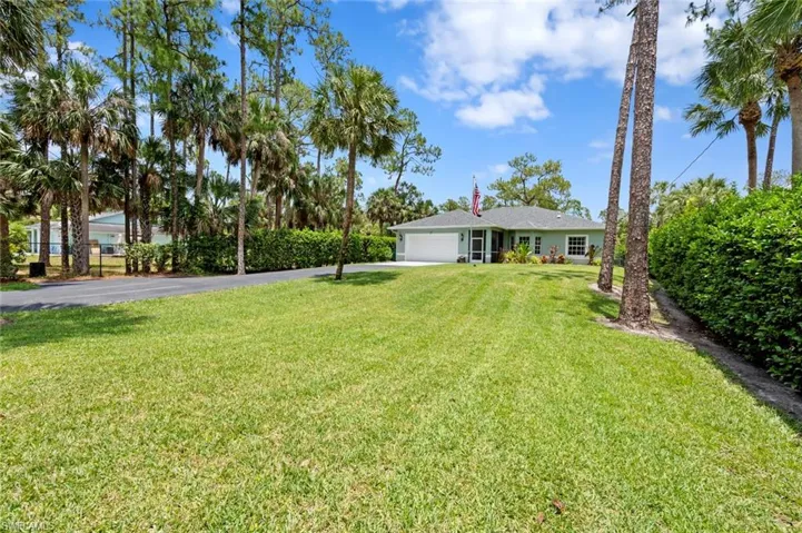 View of front facade with asphalt driveway, an attached garage, and a front lawn