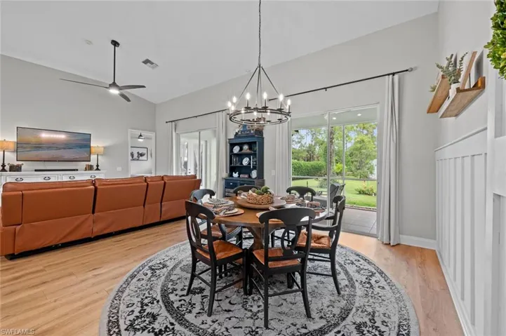 Dining area featuring a chandelier, light wood-style flooring, ceiling fan, and high vaulted ceiling