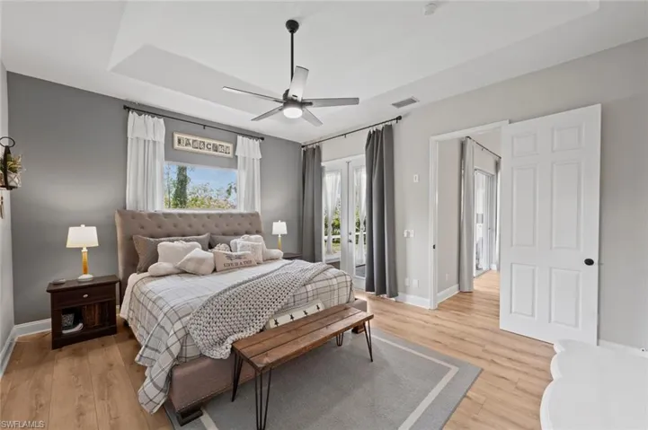 Bedroom featuring access to outside, french doors, a ceiling fan, light wood-style floors, and a raised ceiling