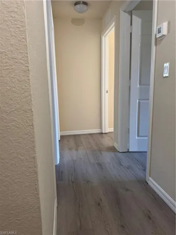 Hall with dark wood-style floors and a textured wall