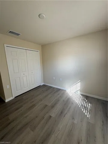 Unfurnished bedroom featuring wood finished floors, a closet, and a textured ceiling