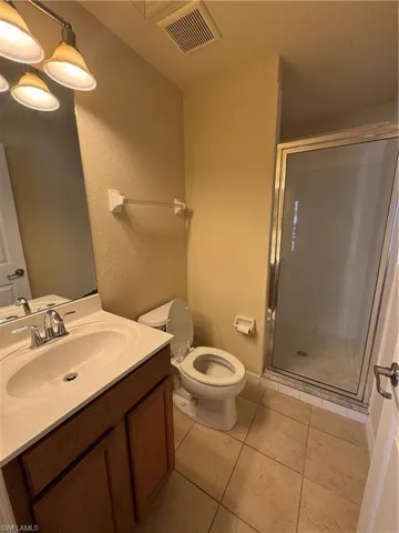 Full bath featuring a stall shower, vanity, a textured wall, and light tile patterned flooring