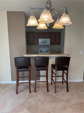 Kitchen featuring a kitchen bar, hanging light fixtures, freestanding range oven, light countertops, and a peninsula