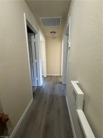 Hallway featuring a textured wall and dark wood finished floors