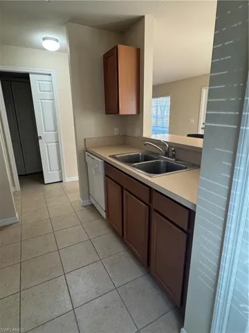 Kitchen featuring light countertops, dishwashing machine, a textured ceiling, and light tile patterned flooring