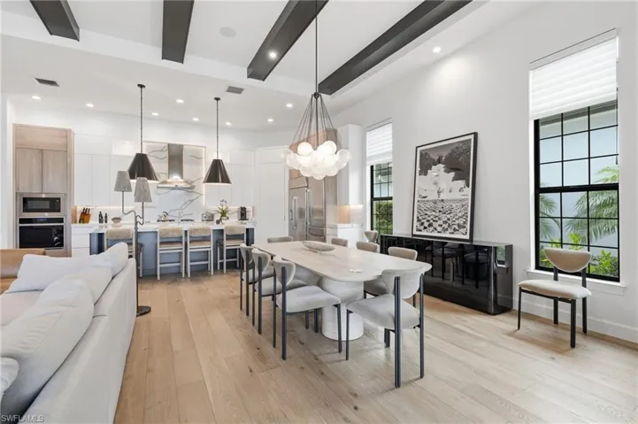 Open-concept interior featuring light wood-finish flooring and high ceilings with exposed beams