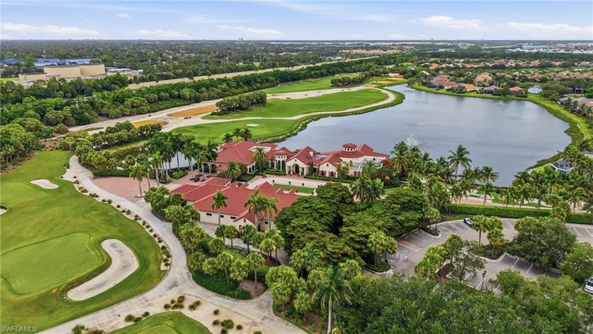 Expansive golf course and water feature surrounding a terracotta-roofed building complex