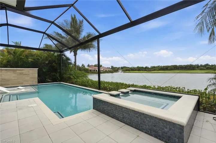 Screened outdoor living area featuring a pool, integrated spa with stone tiling, and a spacious paver deck