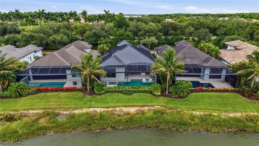 Expansive waterfront property featuring a large residence with multiple screened-in pool enclosures