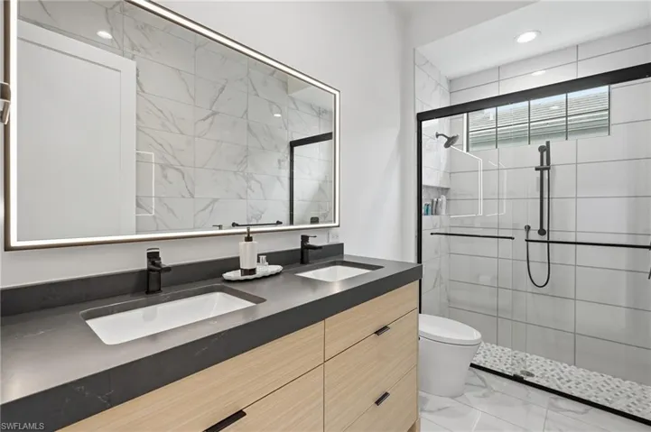 Double vanity with integrated rectangular sinks, dark countertop, and wood-finish cabinetry
