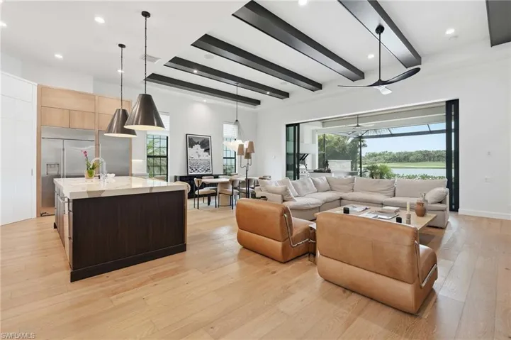 Open-concept interior featuring light wood-finish flooring and high ceilings with exposed beams