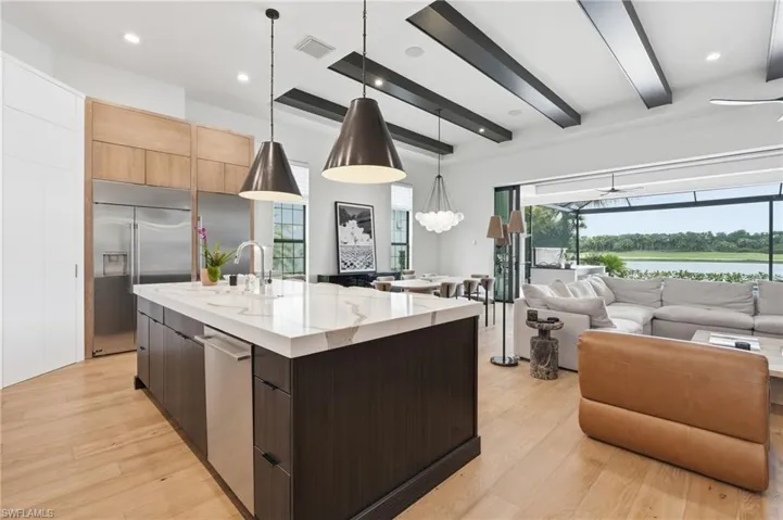 Gourmet kitchen featuring a large island with a waterfall countertop, integrated stainless steel appliances, and wood-finish flooring