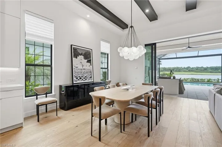 Dining area featuring light wood-finish flooring, a modern chandelier, and exposed ceiling beams