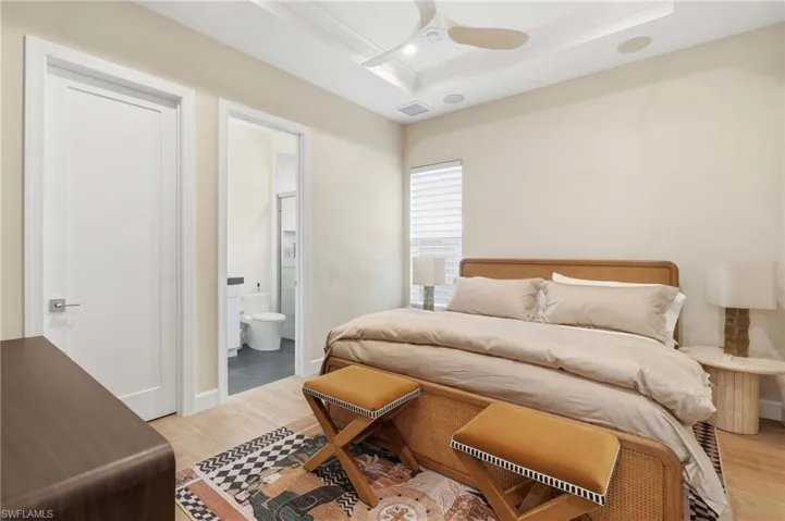 Spacious room featuring wood-finish flooring, a tray ceiling with a modern ceiling fan, and a window with blinds