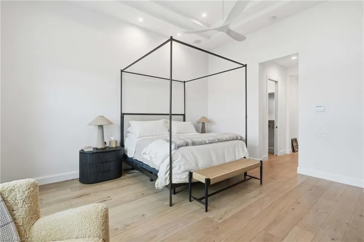 Spacious room featuring light wood-finish flooring and a tray ceiling with a modern ceiling fan