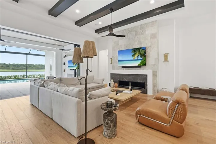 Expansive living area featuring light wood-finish flooring, a contemporary fireplace with a stone surround, and an open-concept design