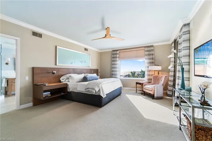 Bedroom with ensuite bath, ceiling fan, carpet flooring, and crown molding