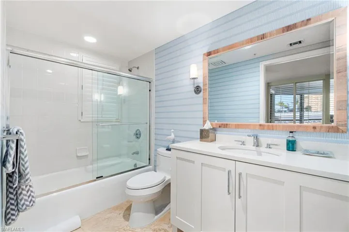 Full bathroom with shower / bath combination with glass door, tile patterned flooring, vanity, and toilet