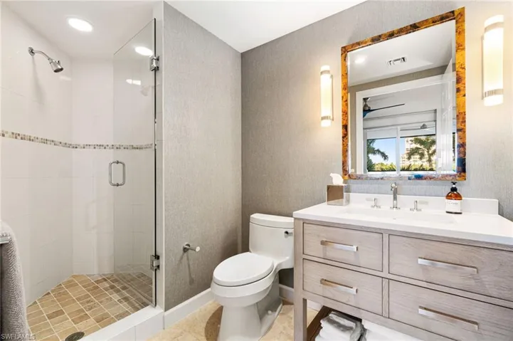 Bathroom featuring tile patterned flooring, vanity, toilet, and a shower with shower door