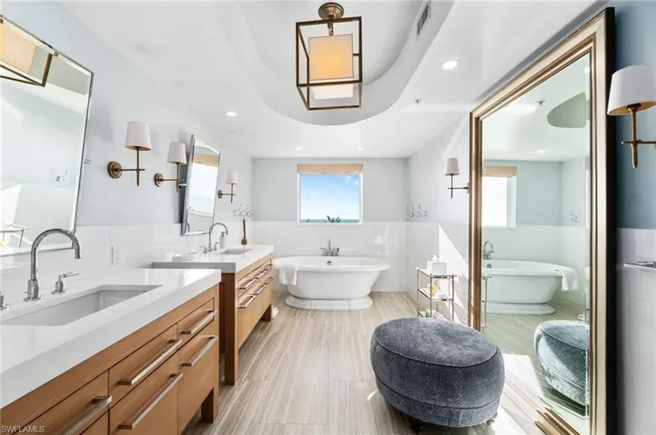 Bathroom featuring tile walls, vanity, tile patterned flooring, and a tub