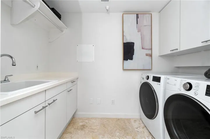Laundry area with separate washer and dryer, sink, and cabinets