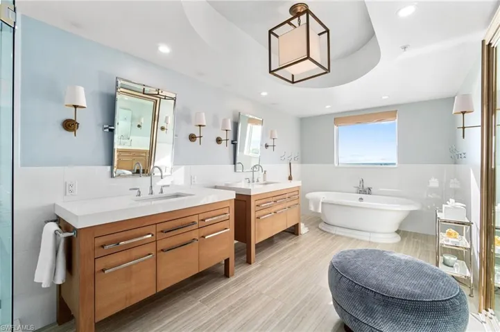 Bathroom featuring vanity, a bathtub, a tray ceiling, and tile walls