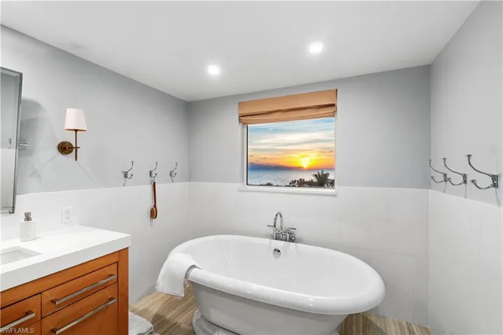 Bathroom with vanity, a bathing tub, and tile walls