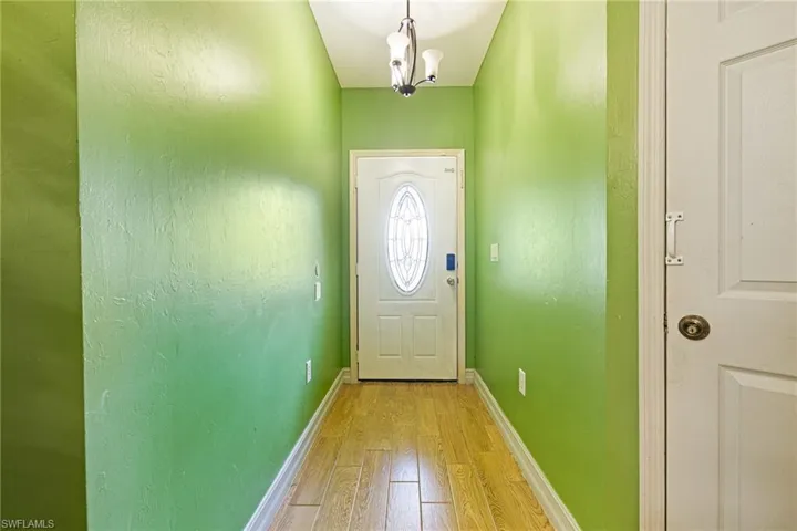 Doorway featuring light wood-type flooring and a chandelier
