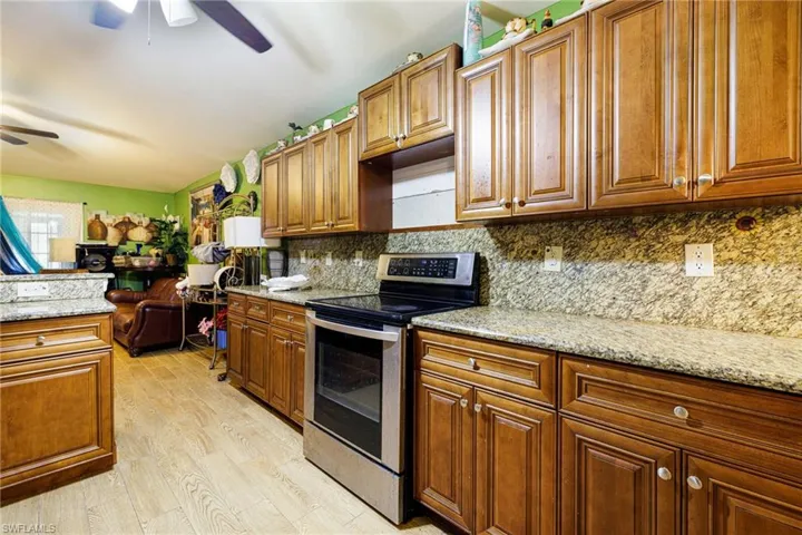 Kitchen featuring stainless steel electric range oven, light wood-style floors, brown cabinetry, and backsplash