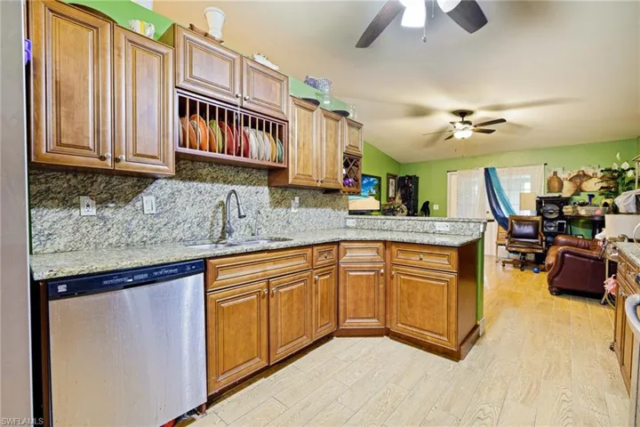 Kitchen with a peninsula, stainless steel dishwasher, light wood-type flooring, backsplash, and brown cabinets