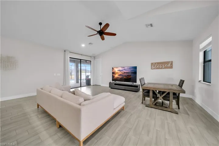 Living area with vaulted ceiling, wood finish floors, and a ceiling fan