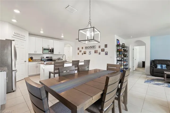 Dining area with arched walkways, hanging lights, and light tile patterned floors