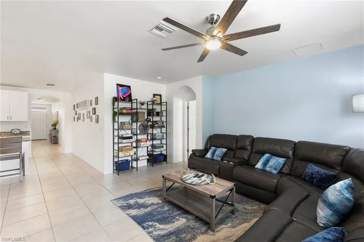 Living area featuring arched walkways, light tile patterned floors, and a ceiling fan