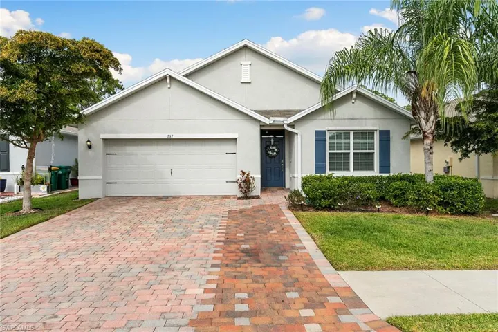 Ranch-style house with a garage, stucco siding, decorative driveway, and a front lawn