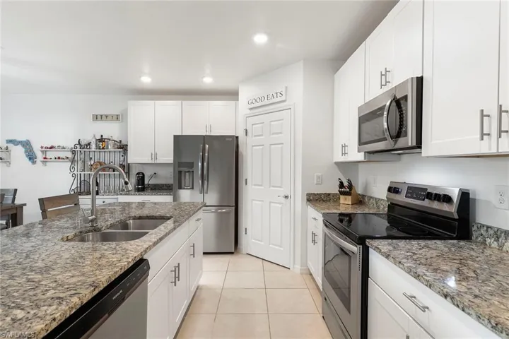 Kitchen featuring stainless steel appliances, light stone counters, white cabinetry, and recessed lighting