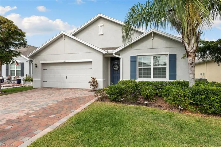 View of front of home with stucco siding, a garage, decorative driveway, and a front lawn