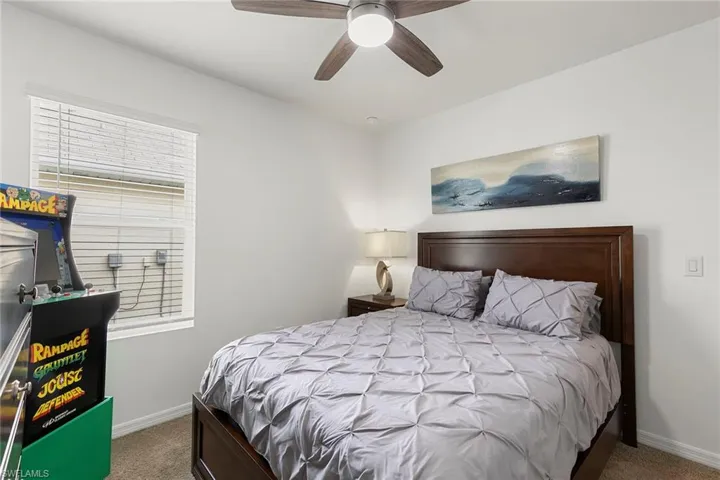 Carpeted bedroom with ceiling fan and baseboards