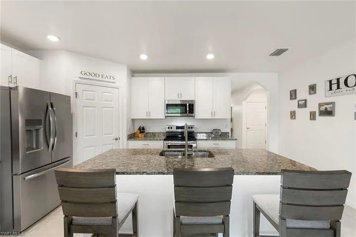 Kitchen with stainless steel appliances, arched walkways, white cabinets, a breakfast bar, and recessed lighting