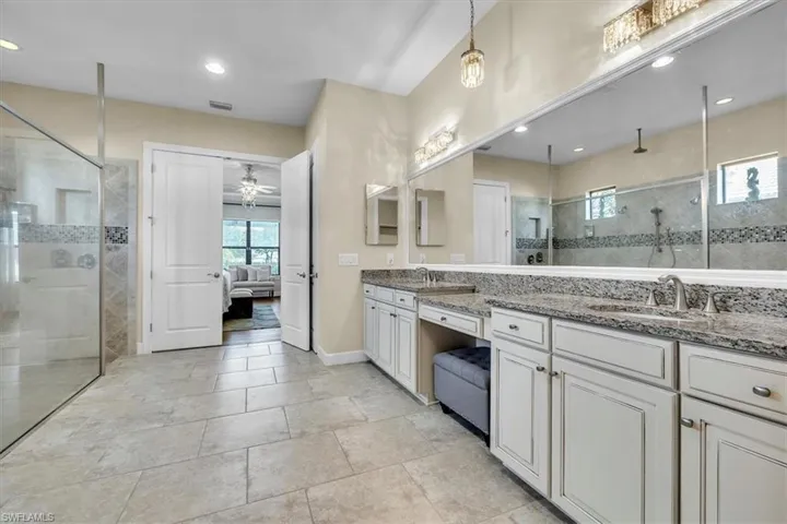 -featuring an oversized walk-in shower, double sinks, framed mirror and a make-up vanity