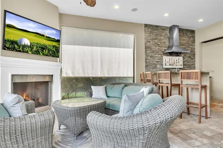 Lanai featuring outdoor kitchen, fireplace, privacy shade, pool/spa, and view of #1 fairway and green