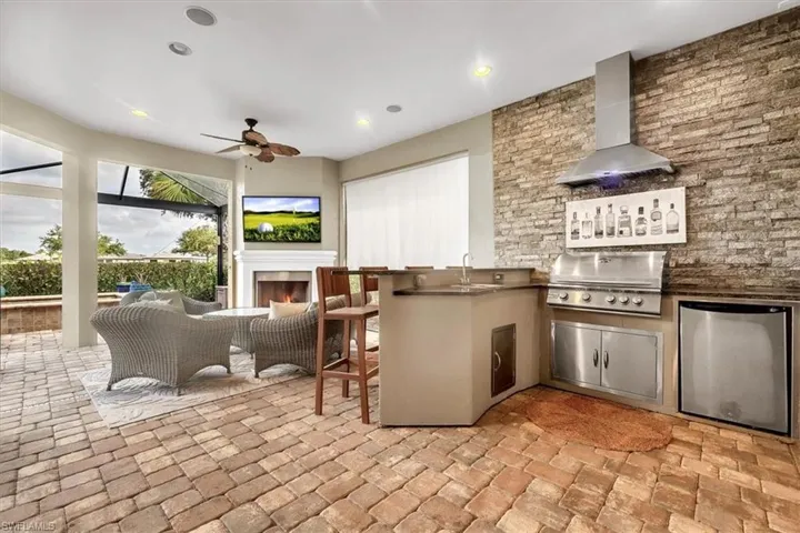Lanai featuring outdoor kitchen, fireplace, privacy shade, pool/spa, and view of #1 fairway and green