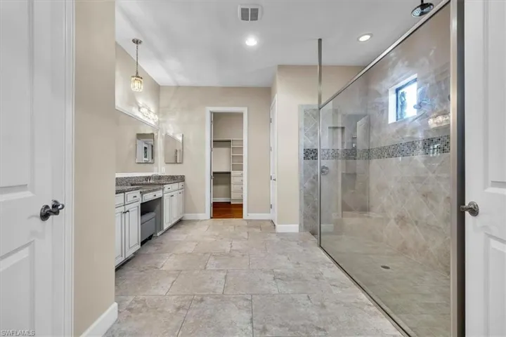 -featuring an oversized walk in shower, double sinks, and a make-up vanity