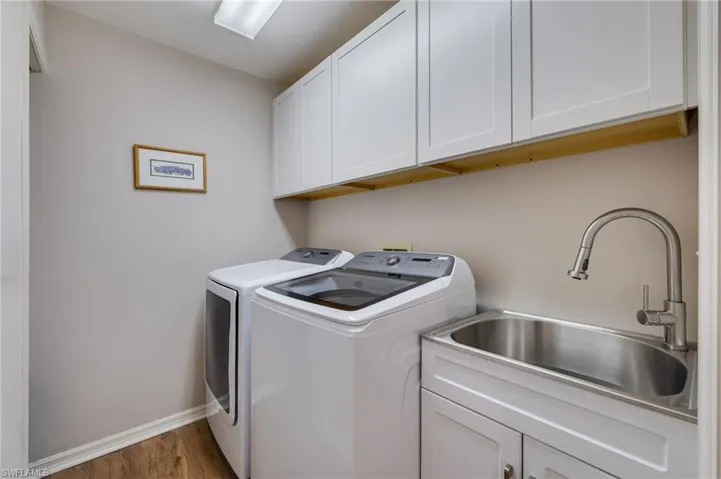 Laundry room complete with newer washer/dryer and new cabinetry and sink.  Additional storage to the left.