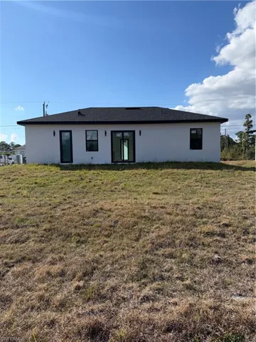 Back of property with stucco siding and a yard