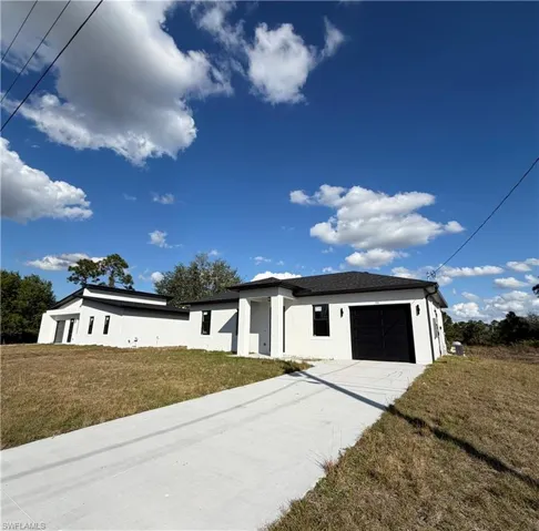 View of front of home with a front lawn, stucco siding, driveway, and an attached garage