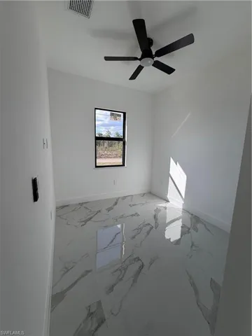 Spare room featuring light marble finish floors and a ceiling fan