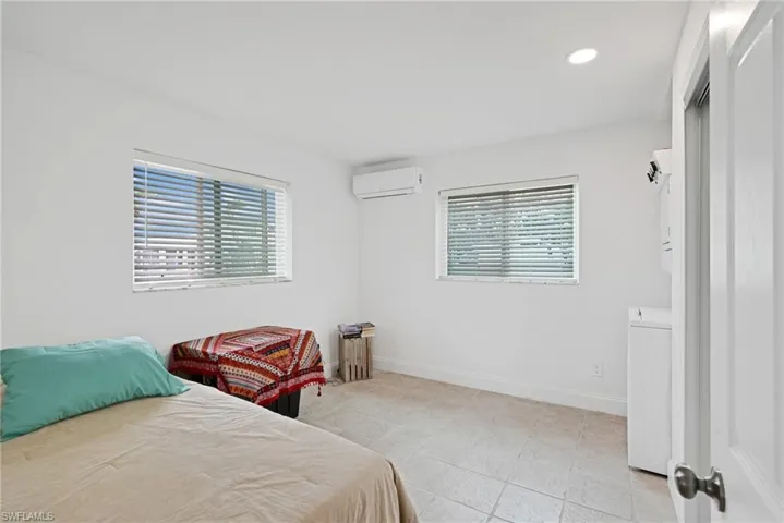 Bedroom featuring a wall mounted AC, light tile patterned floors, and washer / dryer