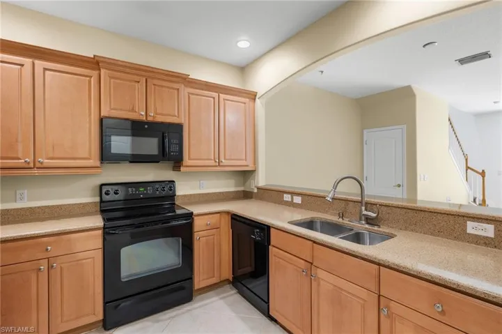 Kitchen with black appliances, light tile patterned floors, light stone counters, recessed lighting, and a peninsula